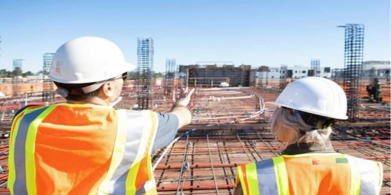 Female & male construction worker looking at construction site